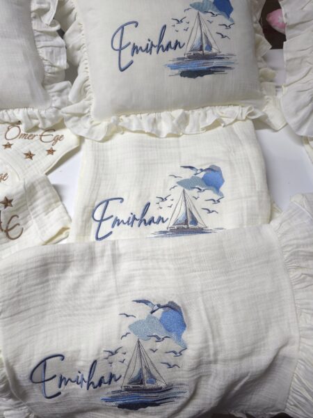 4 katlı %100 pamuk müslin hastane çıkışı seti (0–3 ay); isimli nakışlı tulum, şapka, alt üst takım, eldiven, önlük, battaniye, puset örtüsü ve kırlent ile eksiksiz bir yenidoğan seti sunar.