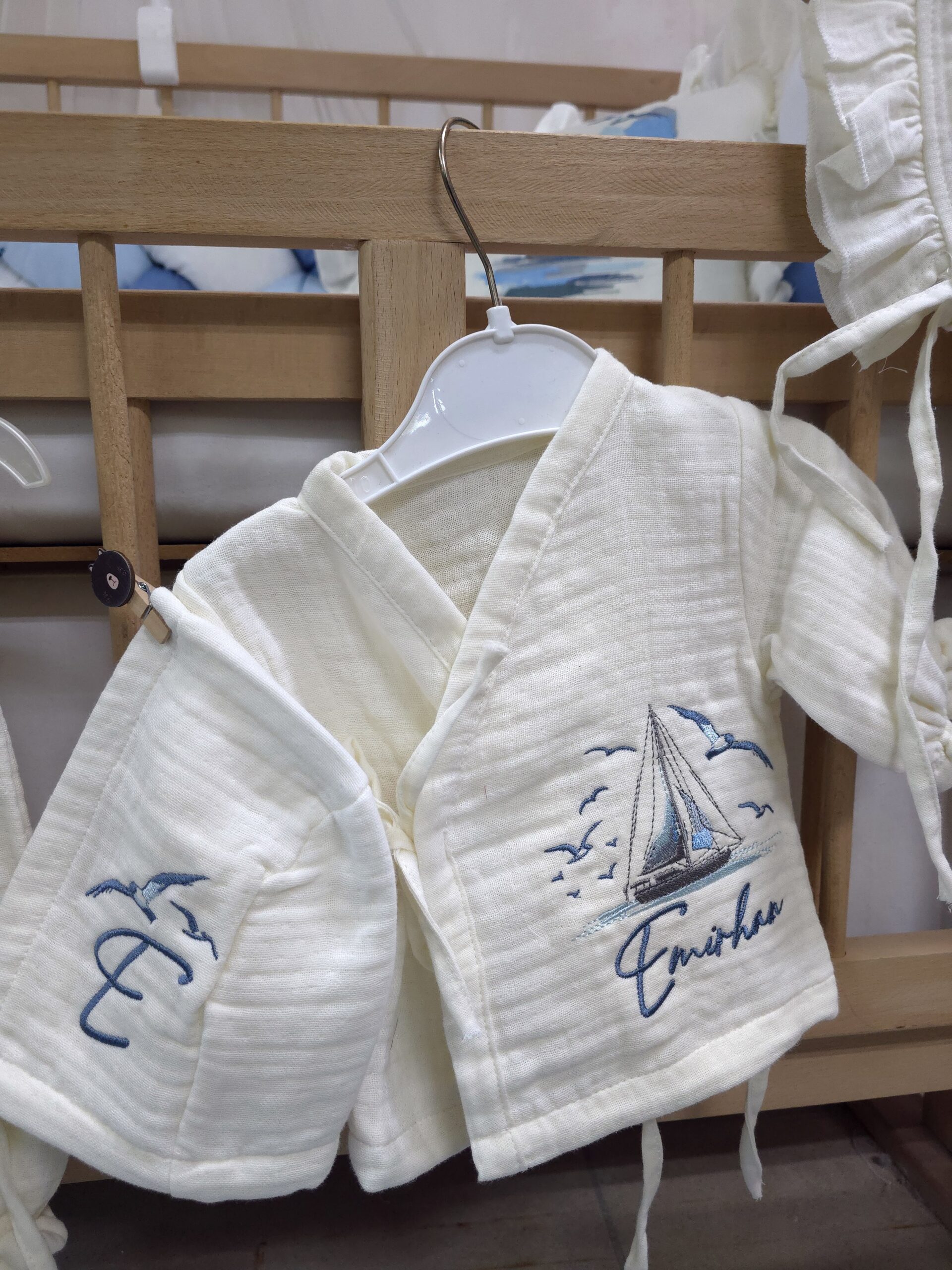 müslin-hastane-çıkışı-T13-(5) 4 katlı %100 pamuk müslin hastane çıkışı seti (0–3 ay); isimli nakışlı tulum, şapka, alt üst takım, eldiven, önlük, battaniye, puset örtüsü ve kırlent ile eksiksiz bir yenidoğan seti sunar.