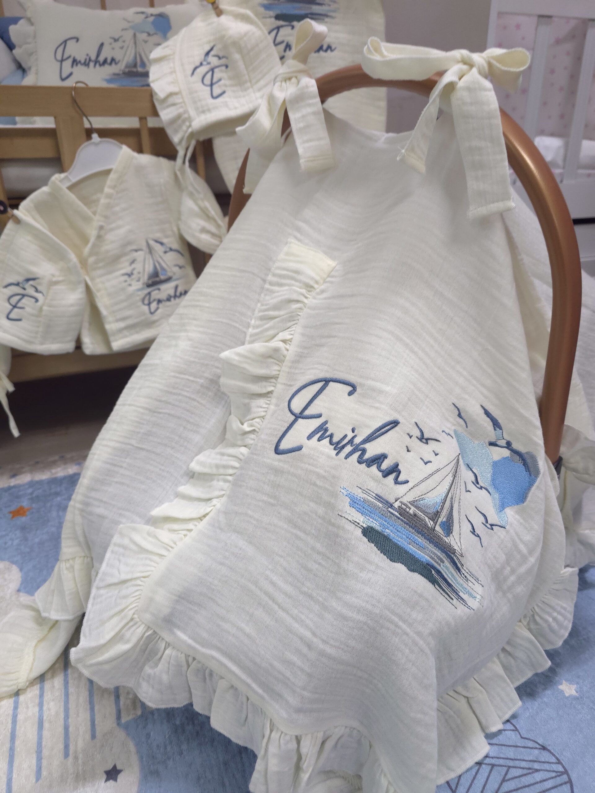 müslin-hastane-çıkışı-T13-(8) 4 katlı %100 pamuk müslin hastane çıkışı seti (0–3 ay); isimli nakışlı tulum, şapka, alt üst takım, eldiven, önlük, battaniye, puset örtüsü ve kırlent ile eksiksiz bir yenidoğan seti sunar.